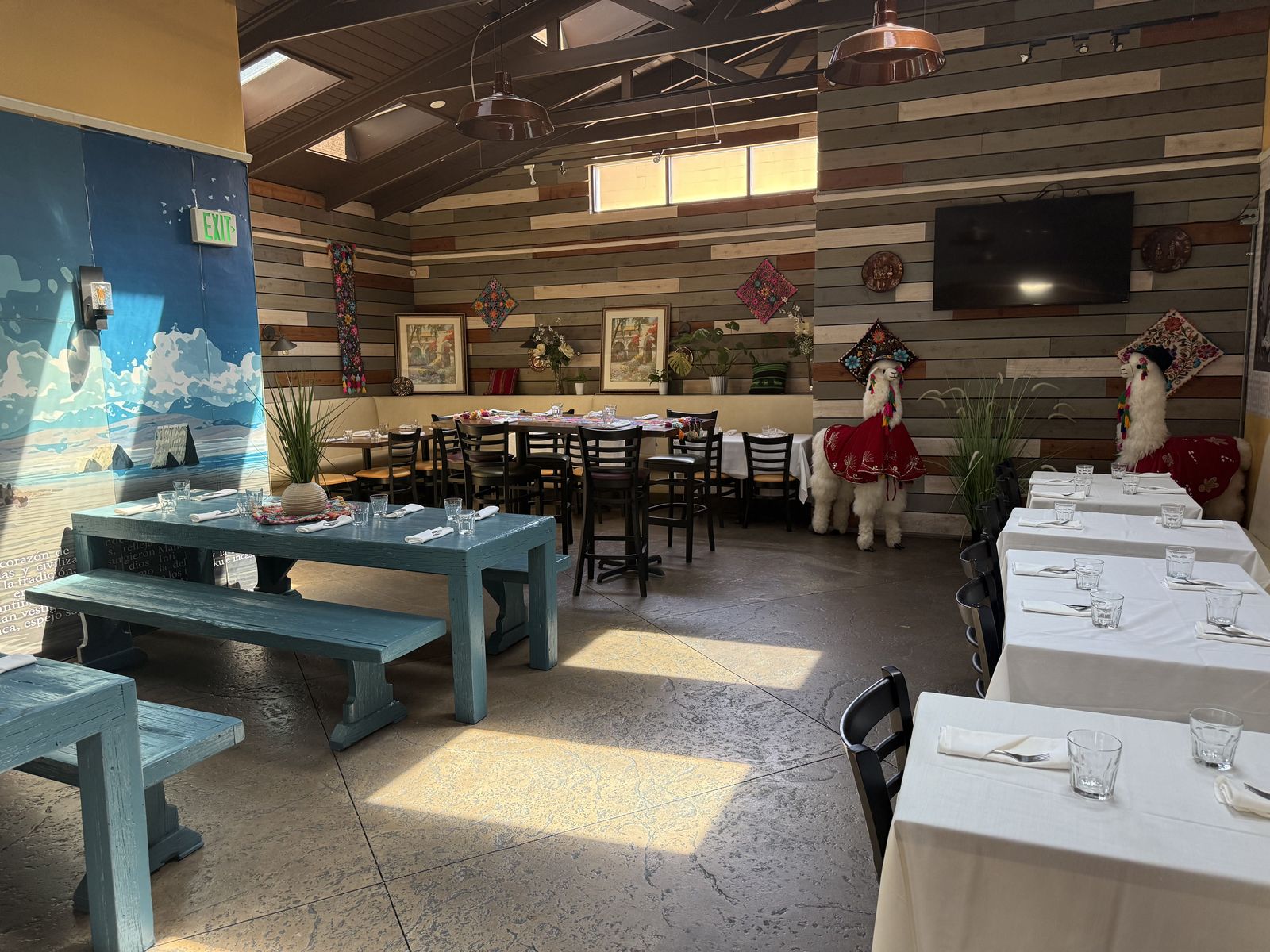 Coya's back dining room with blue tables and an Andean mountain mural