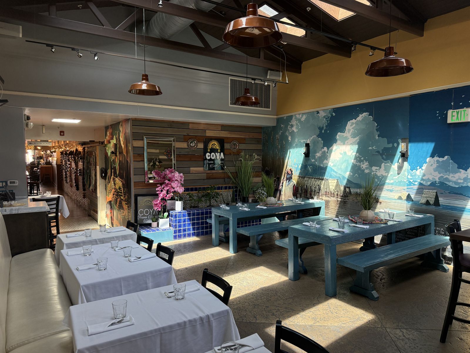 Coya's dining room with blue tables and an Andean mountain mural